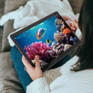 Person holding a COOPERS tablet displaying vibrant underwater coral reef imagery